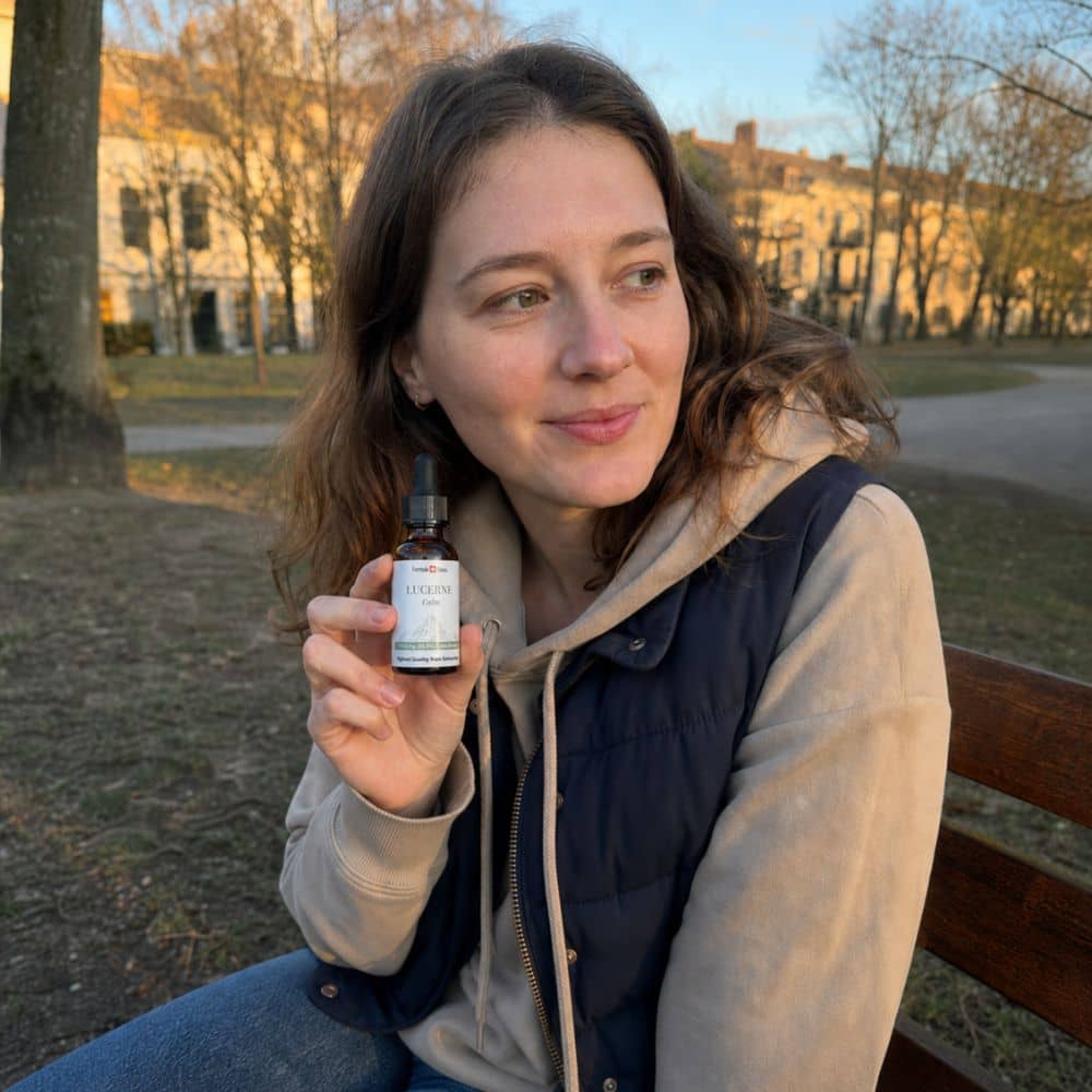 Kvinne som holder en flaske Lucerne CBD-olje utendørs i en park
