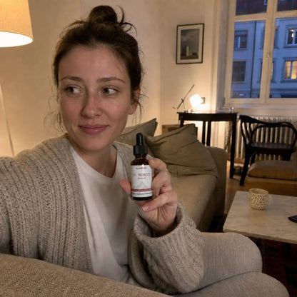 Kvinne som holder en flaske St. Moritz CBD-olje i en stue